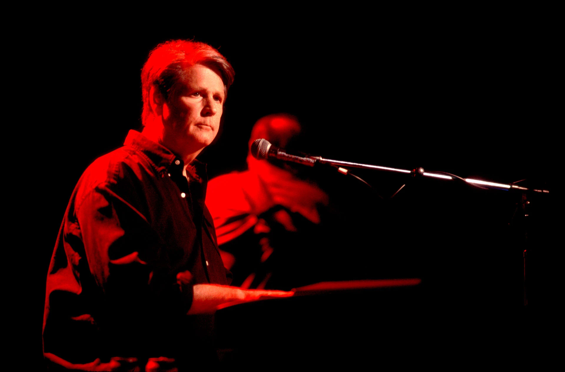 Американский рок- и поп-музыкант Брайан Уилсон играет на клавишных инструментах во время выступления на сцене театра Roxy в Лос-Анджелесе, 2000 год