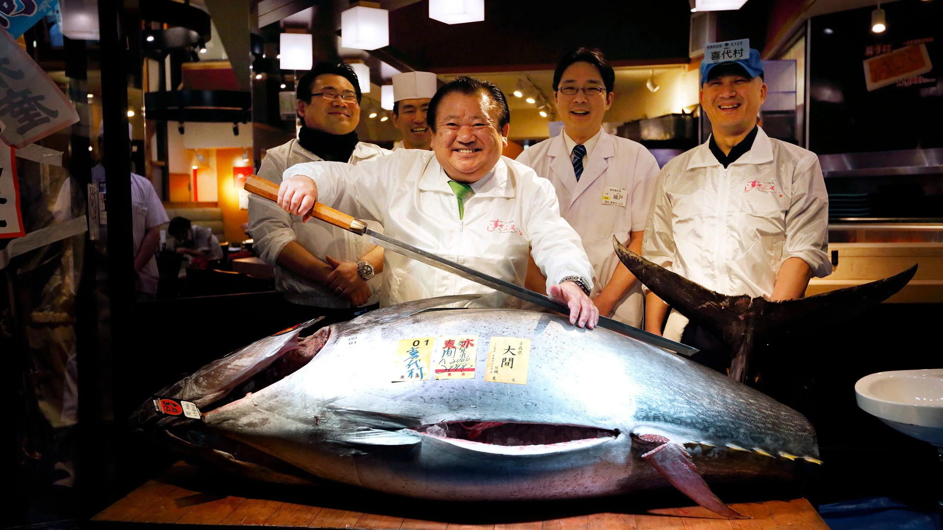 Президент компании Kiyomura K.K. Киёси Кимура (в центре) позирует со свежим голубым тунцом перед одним из суши-ресторанов компании Sushi Zanmai после первого аукциона года на рынке Цукидзи 5 января 2016 года в Токио | Getty Images